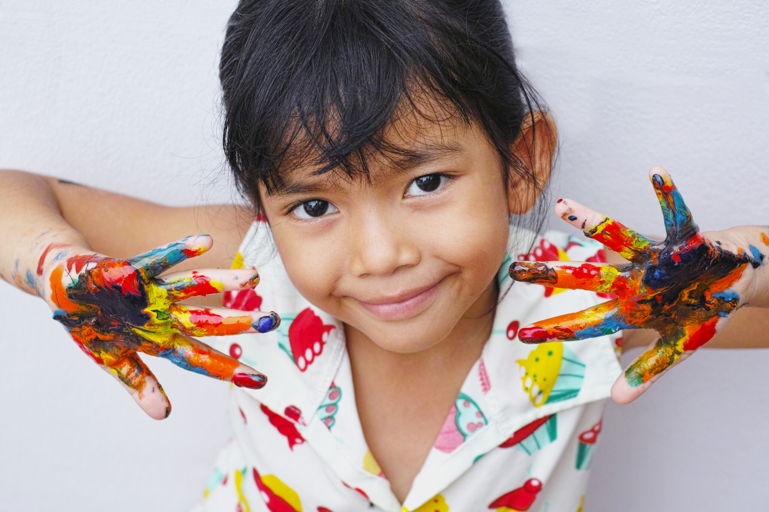 education, school, art and painitng concept - little student girl showing painted hands